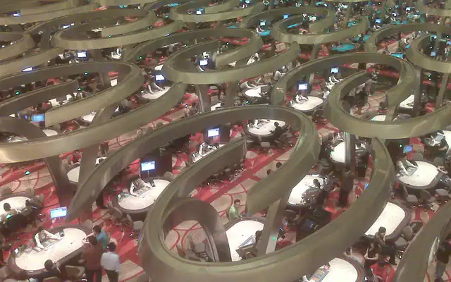Players and dealers at busy baccarat tables on a casino floor